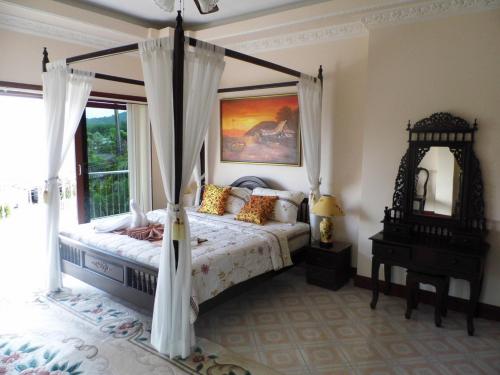 拉威海滩Majestic Villas Guesthouse Phuket.的一间卧室设有天蓬床和窗户。