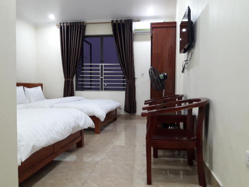 下龙湾Guesthouse Anh Khang的一间卧室设有两张床,墙上配有电视。
