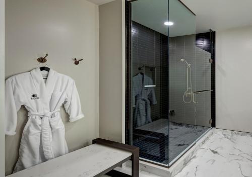 康科德The Hotel Concord的带淋浴和白色浴袍的浴室