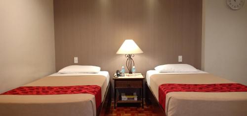 马尼拉Tropicana Suites的两张床位于带灯的房间。