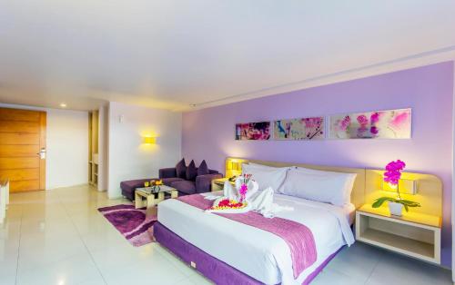 勒吉安Conjioo Hotel Kuta Formerly Instyle Hotel的一间卧室配有一张大床和紫色墙壁