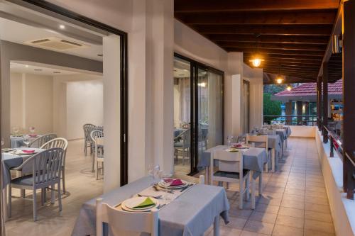 伊利索斯玛图拉海滩酒店的餐厅设有白色的桌椅和窗户。
