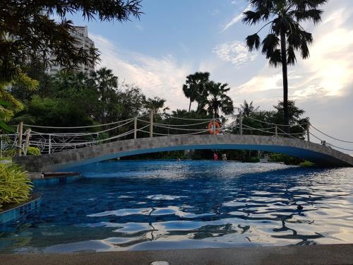 北芭堤雅Beach Front Condominium at The Palm Wongamat的一座水体上的桥梁,一座游泳池