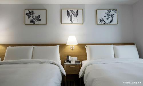 台中市卡尔登饭店台中馆的配有2张床铺的酒店客房,配有白色床单和一盏灯