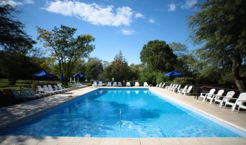 贝尔格拉诺将军镇Howard Johnson Hotel & Spa Villa General Belgrano的一个带白色椅子和蓝天的游泳池