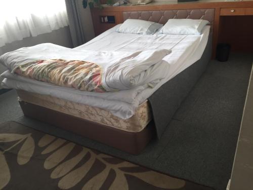 那智胜浦町Katsuura Seaside Hotel的一张带白色床单和枕头的未铺好的床