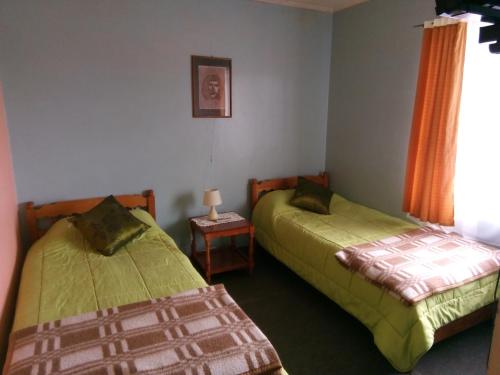 小智利Hotel Ventura的一间卧室配有两张床和一张带台灯的桌子