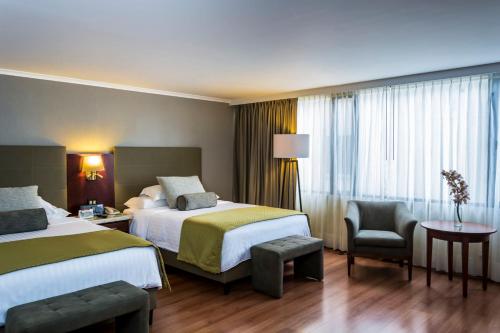 波哥大Bogota Plaza Hotel的酒店客房,配有两张床和椅子