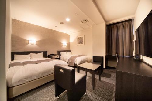 川崎The Grandeur Hotel的酒店客房配有两张床和一张书桌