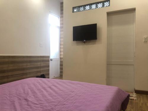大叻Ruby Dalat Hostel的卧室配有一张床,墙上配有电视。
