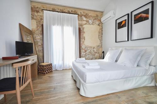 库列拉Alqueria de Vilches的白色卧室设有一张大床和电视。