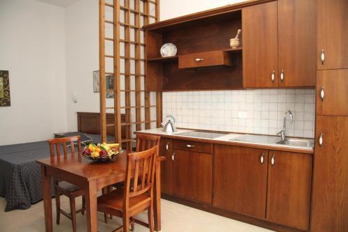 格罗塞托港伊朵皮尼旅馆的厨房配有木制橱柜和1张带水果碗的桌子
