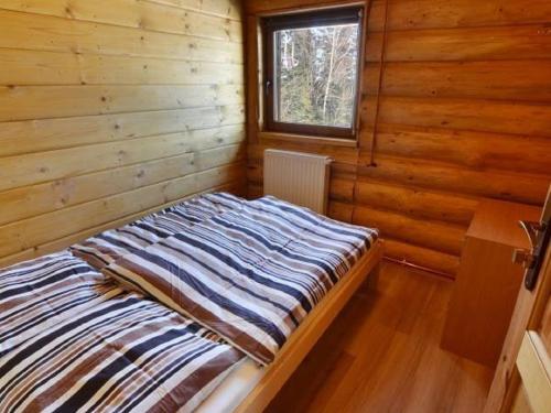 科尔别卢夫Domek Na Stoku的木制客房的一张床位,设有窗户