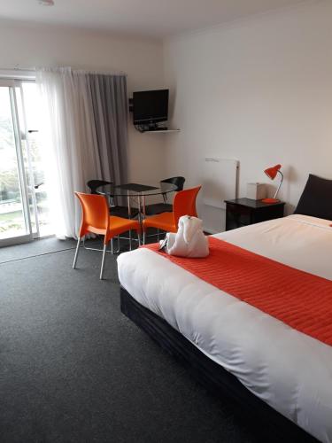 MokauMokau Motels的酒店客房带一张床、一张桌子和椅子