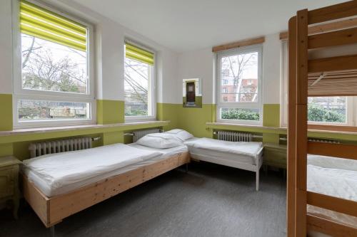 亚琛Hostel Aachen的带三扇窗户的客房内的两张床