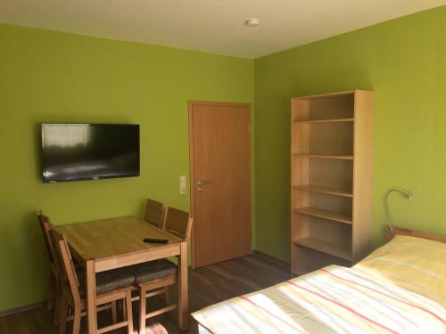 朗斯多夫迈耶饭店的一间设有一张桌子和一张床的房间,一间设有绿色墙壁的房间