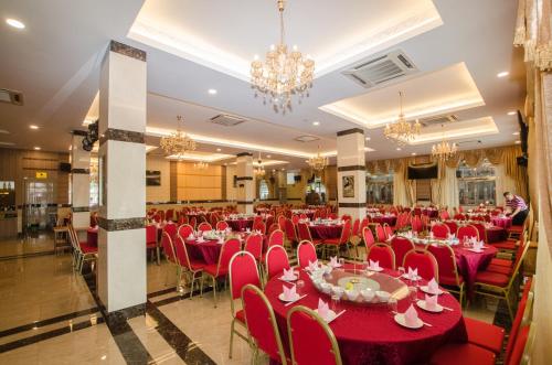 诗巫Grand Wonderful Hotel的宴会厅配有红色的桌椅和吊灯