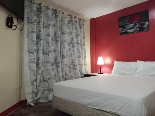 麦克坦Cozy Inn Mactan的一间卧室设有一张大床和红色的墙壁