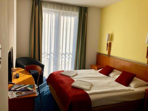 布达佩斯维瑞塔斯酒店的配有一张床、一张书桌和一扇窗户的酒店客房