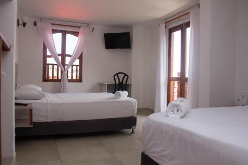卡塔赫纳Akel House Hotel的一间卧室设有两张床和两个窗户。