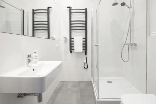 卡托维兹Przystanek Katowice Mariacka 26的白色的浴室设有水槽和淋浴。