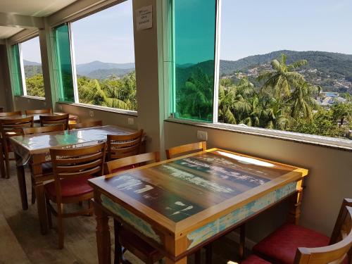 布卢梅瑙Pousada Do Galdino的餐厅设有桌椅和大窗户。
