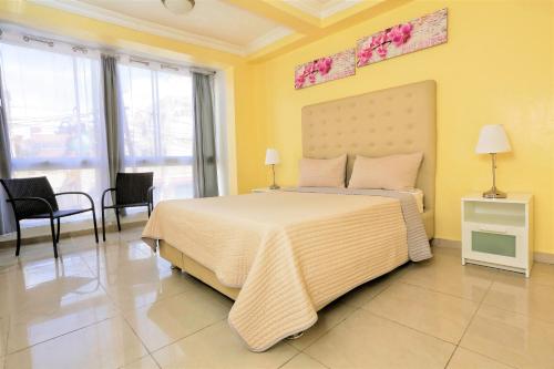 圣多明各RIG Puerto Malecón的一间卧室设有一张大床,拥有黄色的墙壁和窗户。