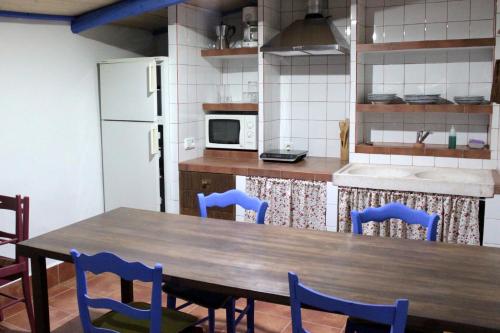 Corral de CalatravaCasa Rural La Alfarera的厨房配有木桌和蓝色椅子