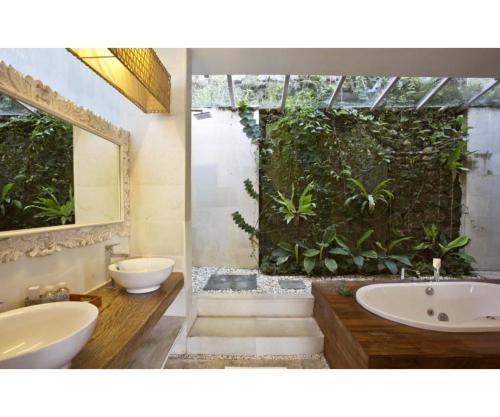 乌鲁瓦图乌鲁瓦图日落天堂别墅的浴室配有两个盥洗盆、浴缸和植物