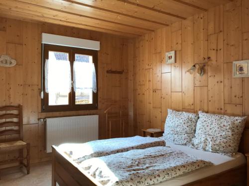 苏茨马特Les Berges de l'Ohmbach的一间卧室配有一张带木墙和窗户的床。