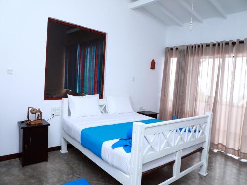 米瑞莎Fresh Wave Mirissa - Beach Front的一间卧室配有一张白色的床和蓝色的毯子