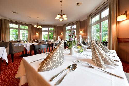 TauerChristinenhof & Spa - Wellnesshotel am Rande des Spreewalds的用餐室配有白色桌子和银器