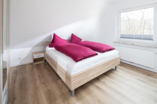 诺德奈Deniz - Blick的白色客房内的一张带紫色枕头的床