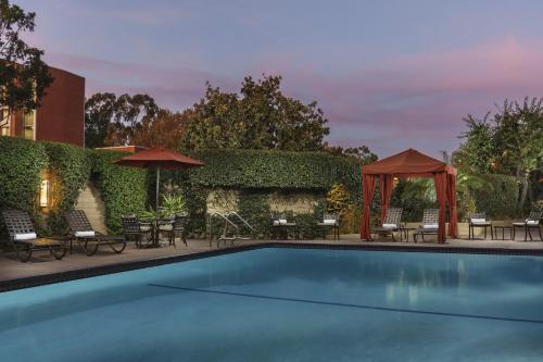 洛杉矶USC Hotel的一个带椅子和遮阳伞的游泳池