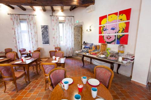 博讷阿塔诺中心酒店的餐厅设有桌椅,墙上挂有绘画作品