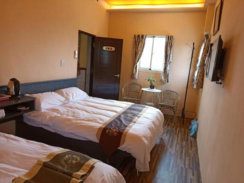 金宁乡喜樂居的酒店客房设有两张床、一张桌子和一个窗户。