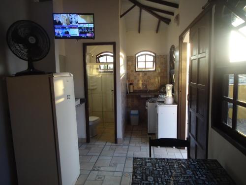 卡波布里奥Vila do Sossego的带冰箱的厨房和墙上的电视