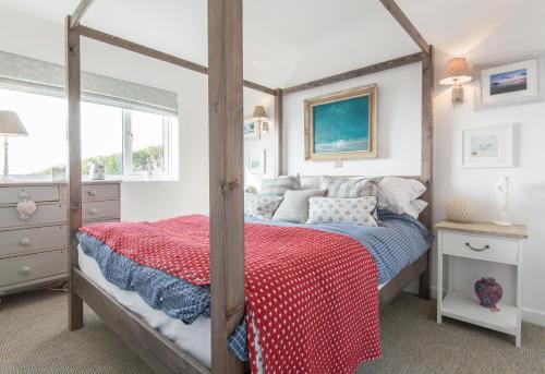 森嫩湾Creagle, Sennen Cove的一间卧室配有一张带红色毯子的天蓬床