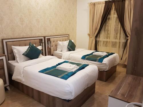 尼兹瓦Orient Apartments的配有窗户的酒店客房内的两张床