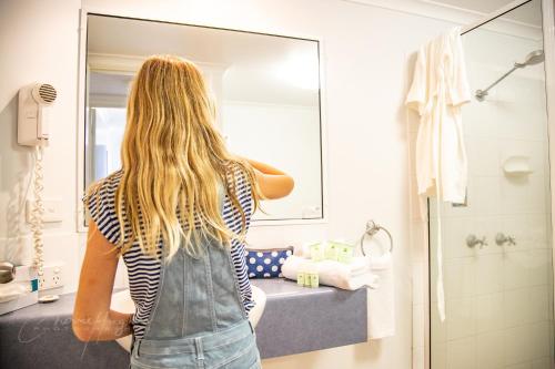 麦凯Mackay Seabreeze Apartments的女人在浴室镜子里看着她的反射