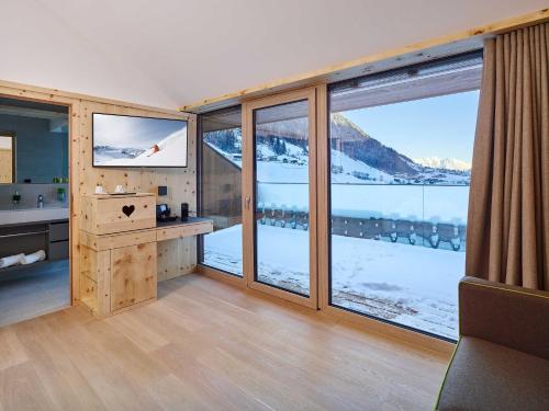 施图拜河谷新施蒂夫特阿尔佩尼尔 - 蒂罗尔自然度假酒店的客房设有大窗户,享有雪覆盖的山脉美景。