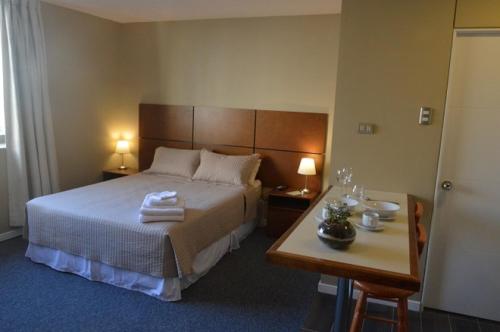 圣地亚哥Origen Apart-Hotel的一间卧室配有一张床和一张带两盏灯的桌子。