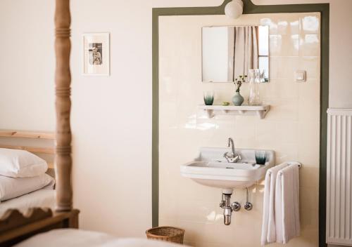 若特阿赫-埃根Berghotel Altes Wallberghaus的浴室设有水槽和床边的镜子