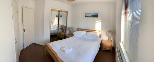 阿伯丁布卢姆菲尔德 - 阿伯丁服务式公寓的一间卧室配有一张带白色床单和镜子的床