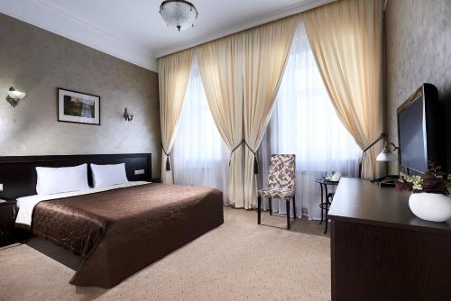奥布宁斯克Hotel Imperial Wellness & SPA的一间卧室配有一张床、一张书桌和一台电视