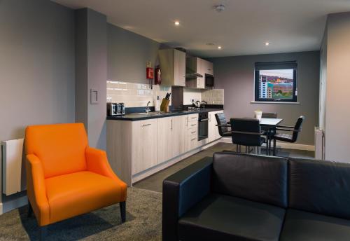泰恩河畔纽卡斯尔Luxury Apartments Newcastle的一个带橙色椅子的客厅和一个厨房