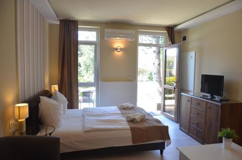 蒂豪尼阿德勒酒店及健康中心的一间卧室配有一张带电视的床和滑动玻璃门。