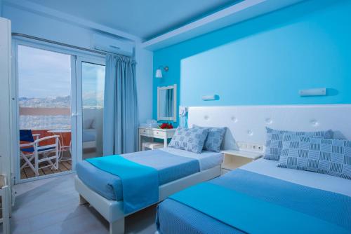 玛利亚Kastro Beach Apartments的一间蓝色卧室,配有两张床和一个阳台