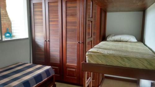 瓜鲁雅Cobertura Enseada Guarujá的一间卧室配有一张床和一个带木门的衣柜