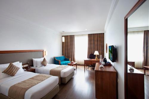 科钦Monsoon Empress Kochi的酒店客房设有两张床和电视。
